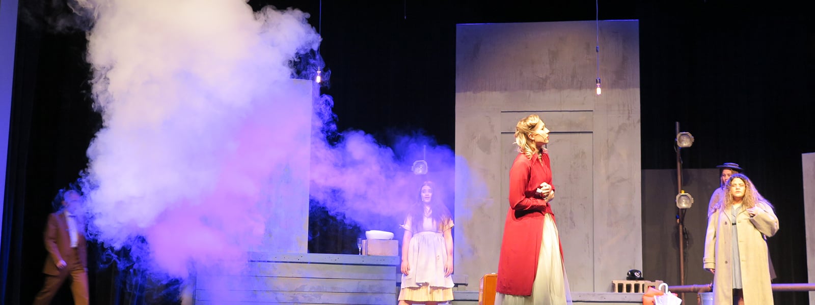 Students acting on a stage with fog.