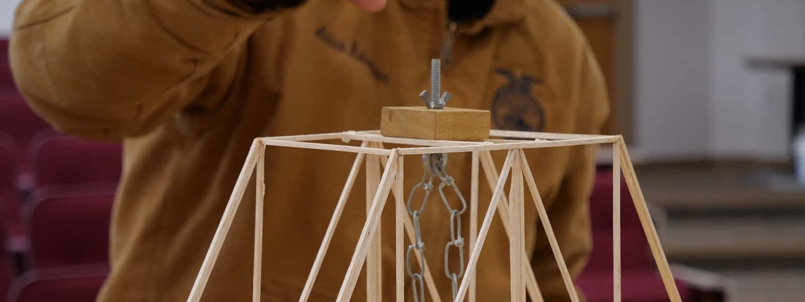 An engineering student works on a model bridge project.