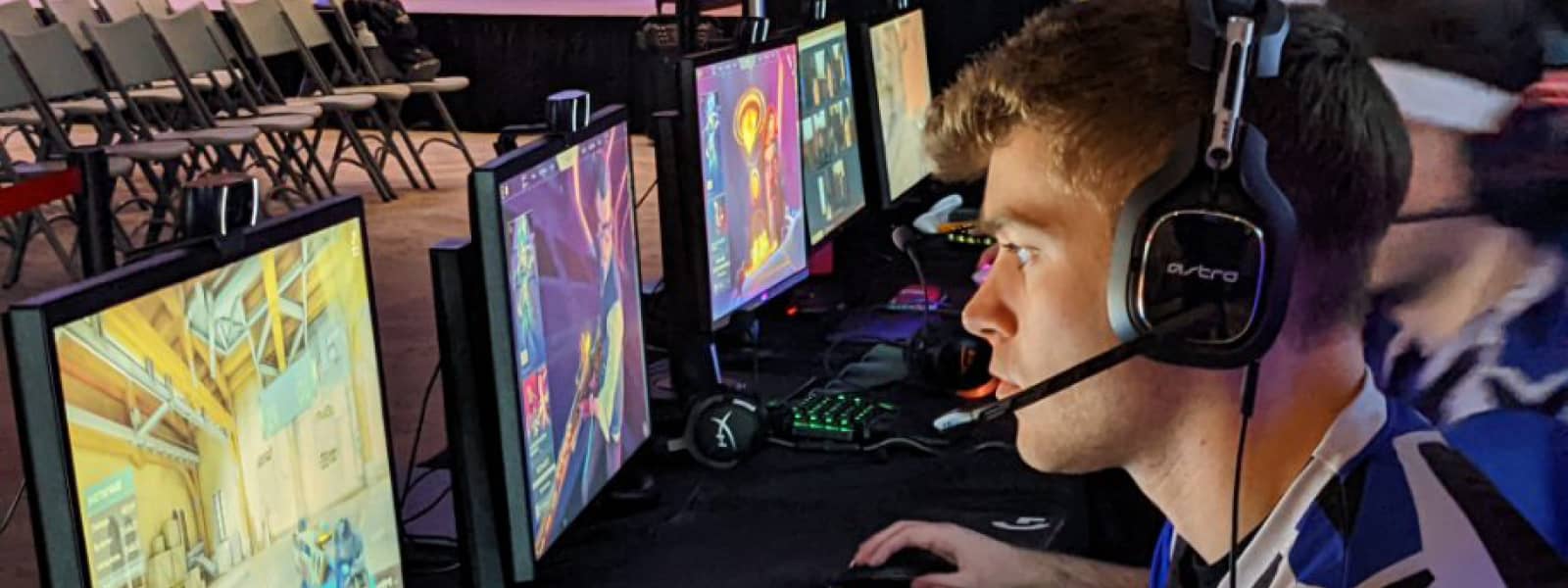 Esports player with a headset on playing a game at a computer.