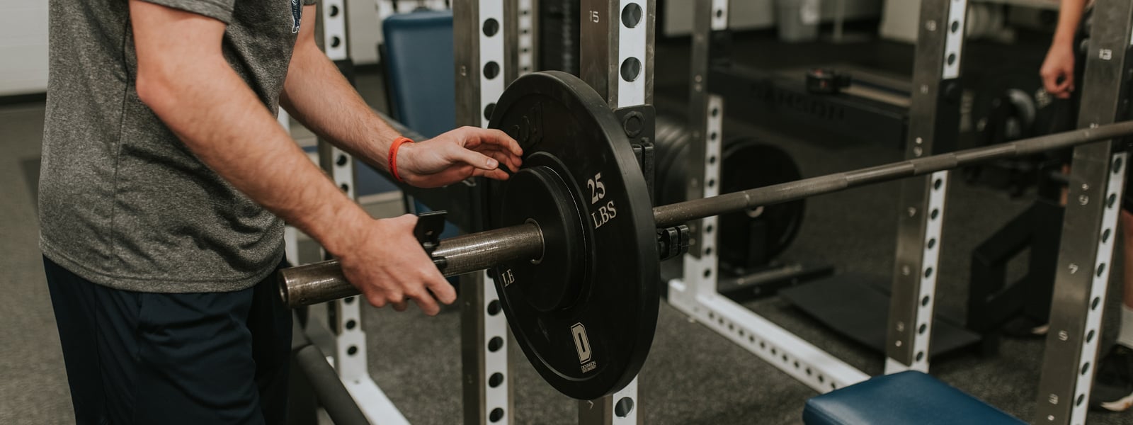 A student puts weights on a barbell.