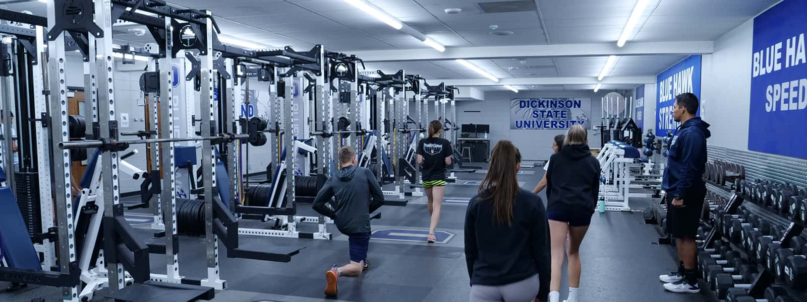 Students in a facility with a variety of exercise equipment. 