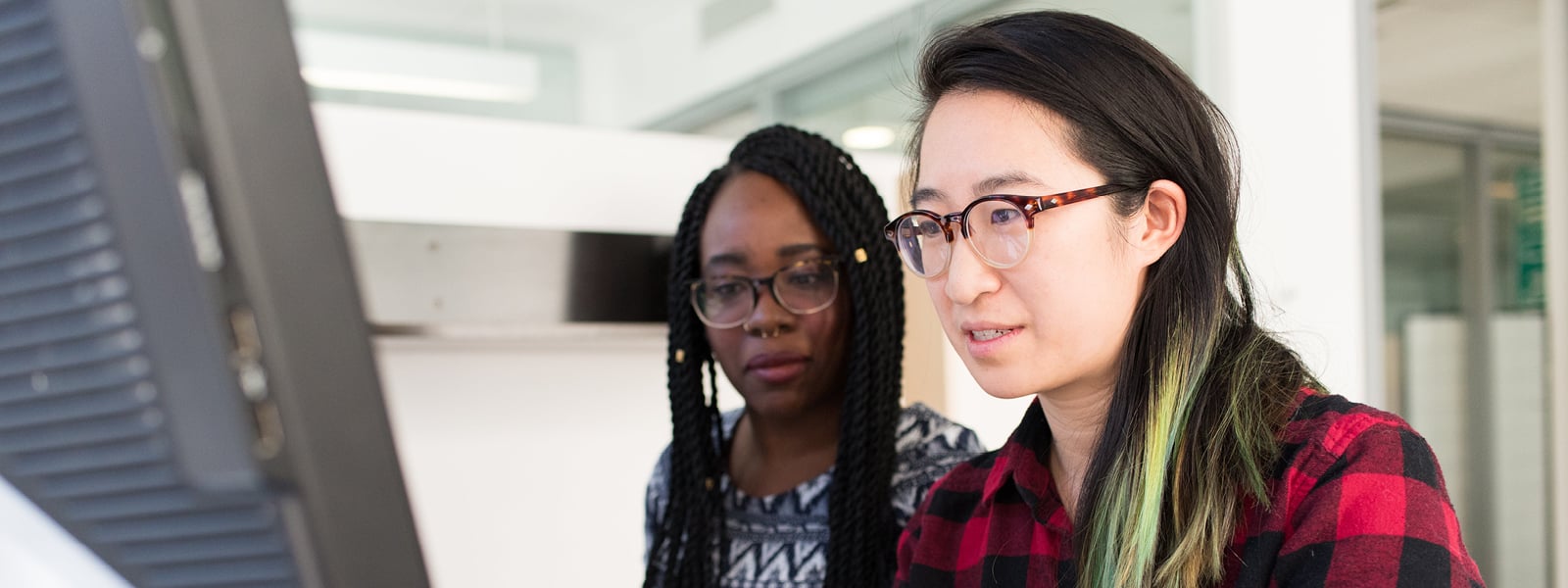 Two students look at a computer screen.