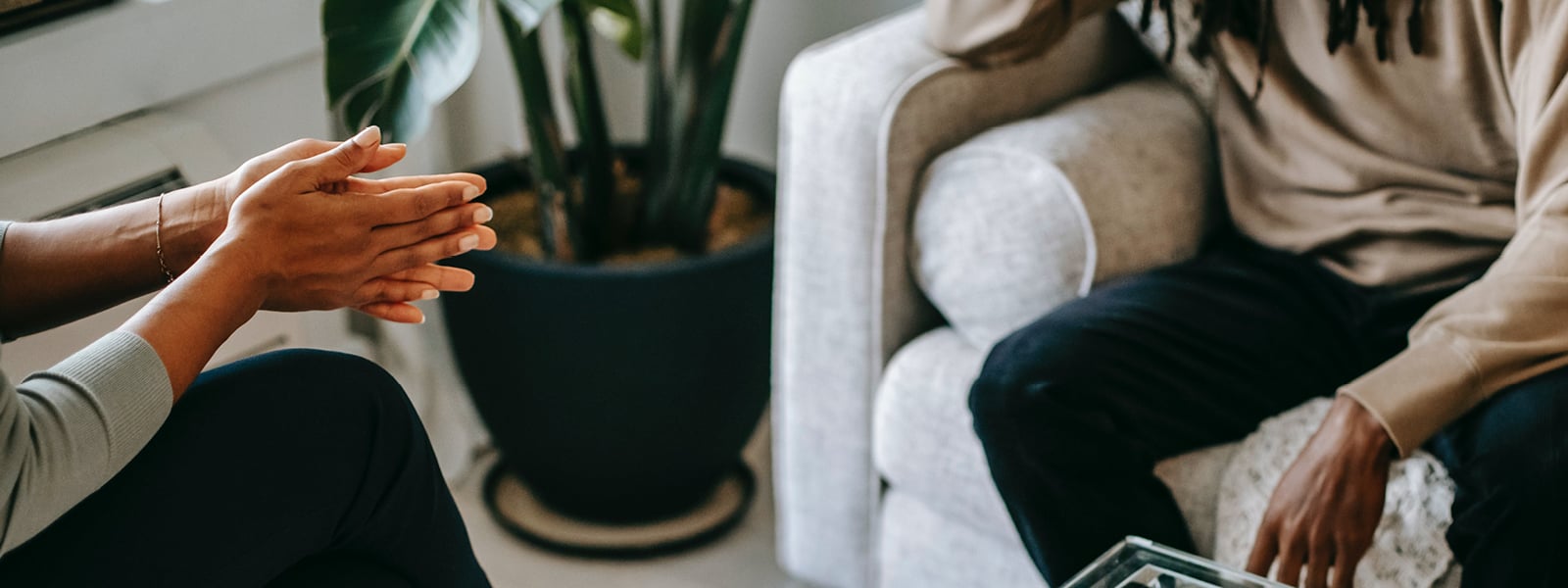 A therapist speaks to a man sitting on a couch. 