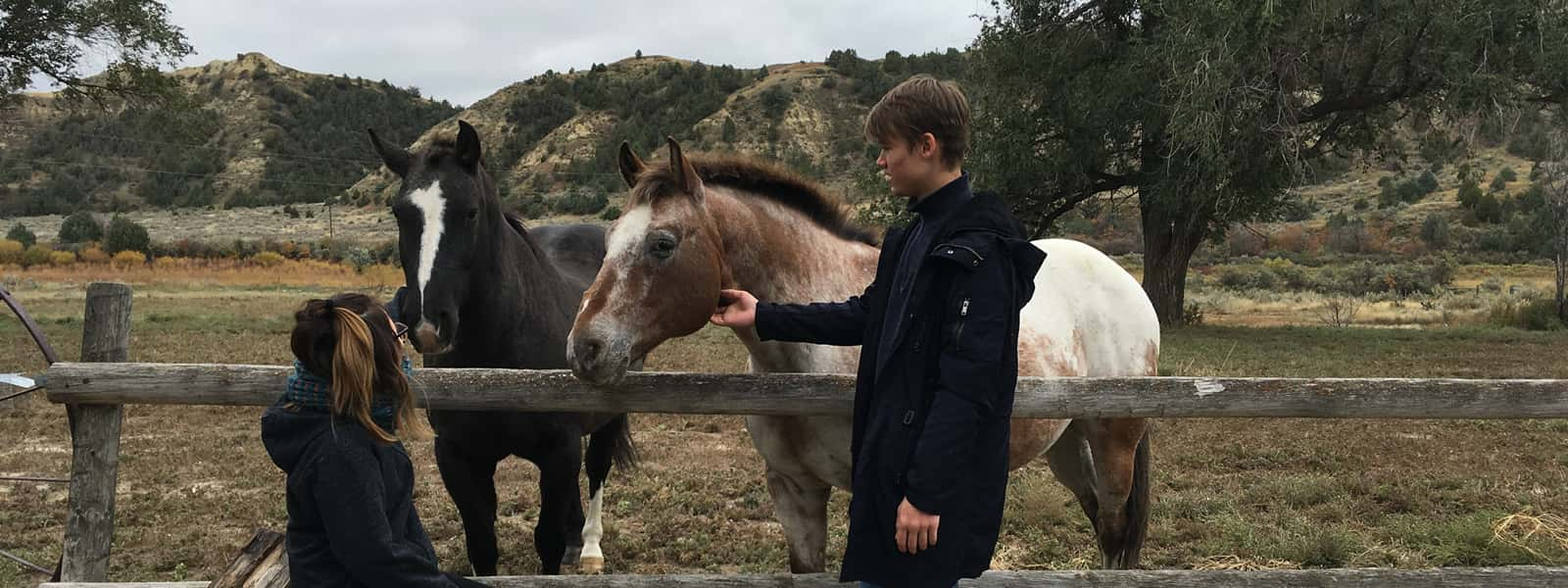 Two people standing next to two horses. 