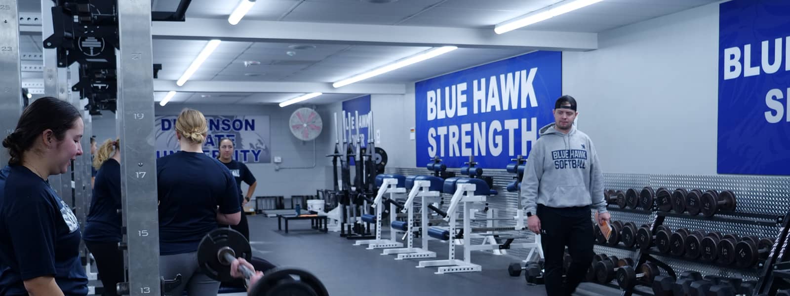 Students in a facility containing various pieces of exercise equipment. 