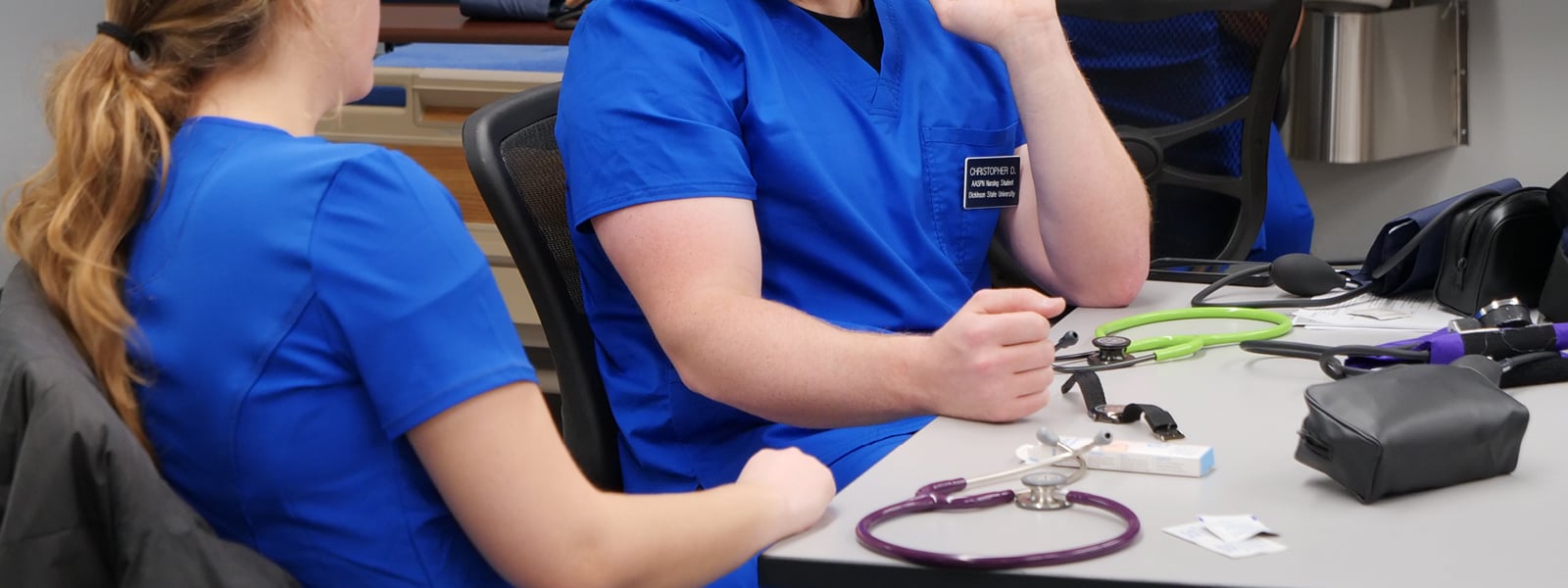 Two nursing students sit at a table talking.